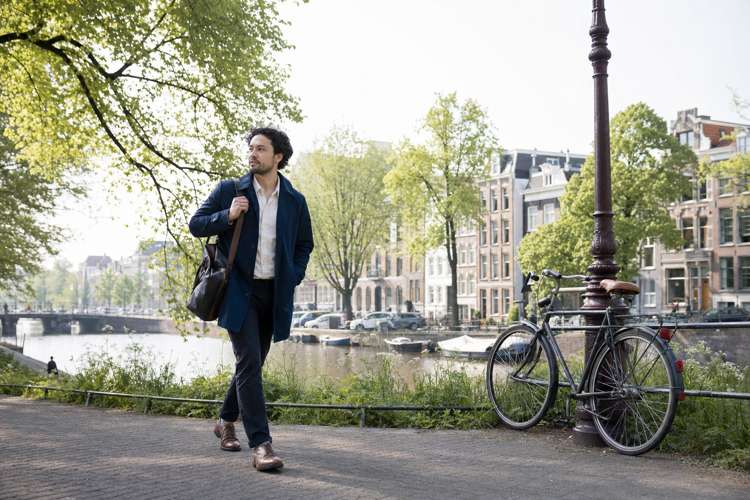 Een man wandelt in de ochtend langs een groene stadsgracht met een werktas
